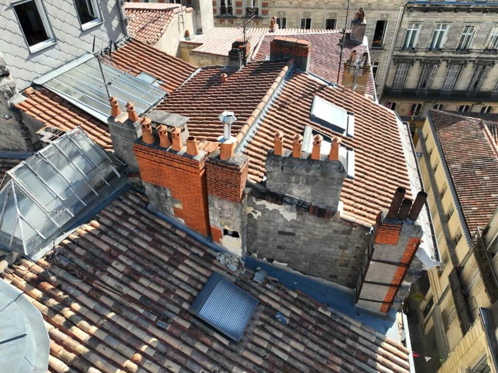 Vue d’ensemble par drone de toitures bordelaises avec souches de cheminée dégradées