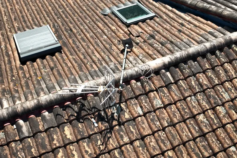 Mât d’antenne TV posé directement sur une toiture en tuiles, sans fixation indépendante, vu par drone