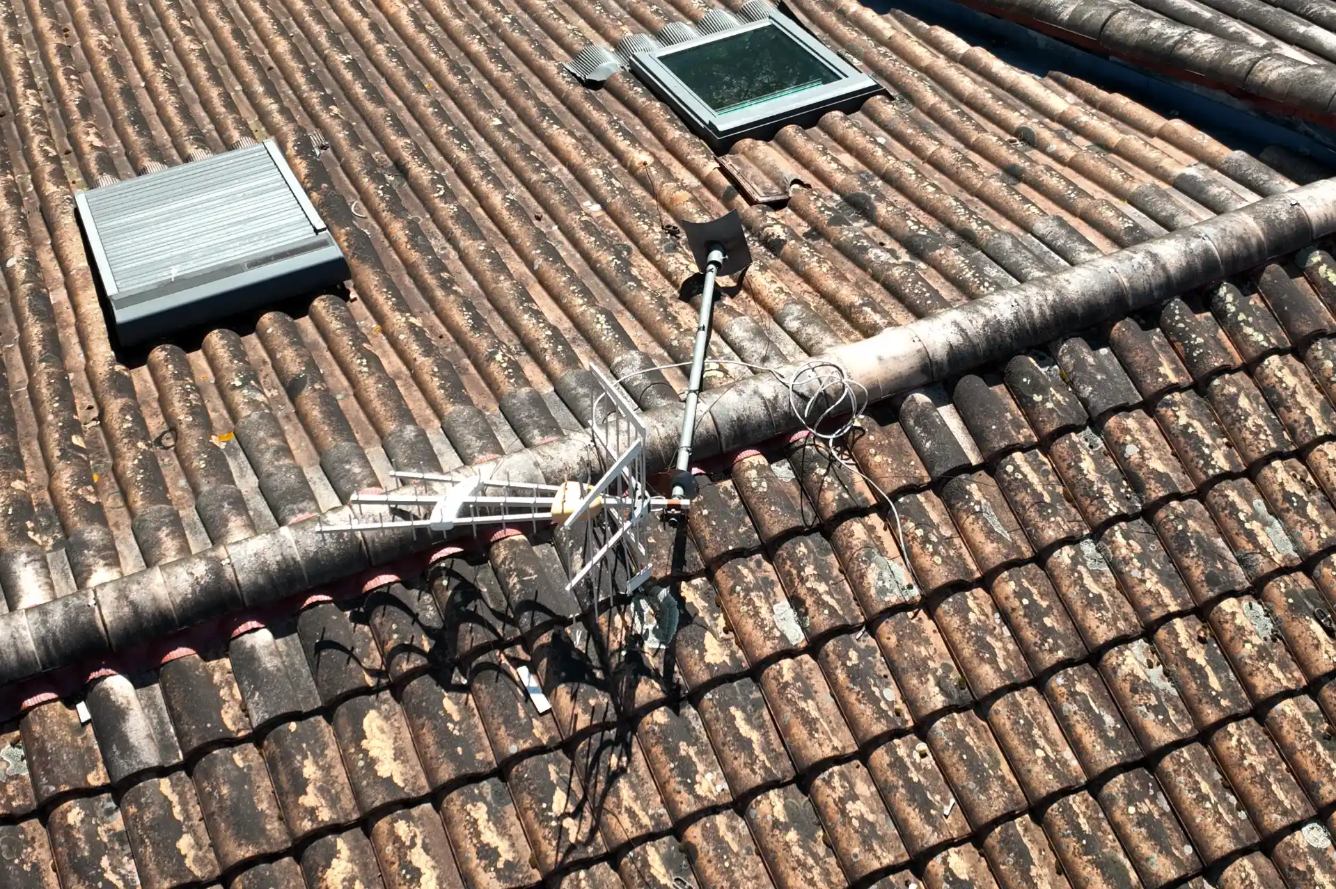 Mât d’antenne TV posé directement sur une toiture en tuiles, sans fixation indépendante