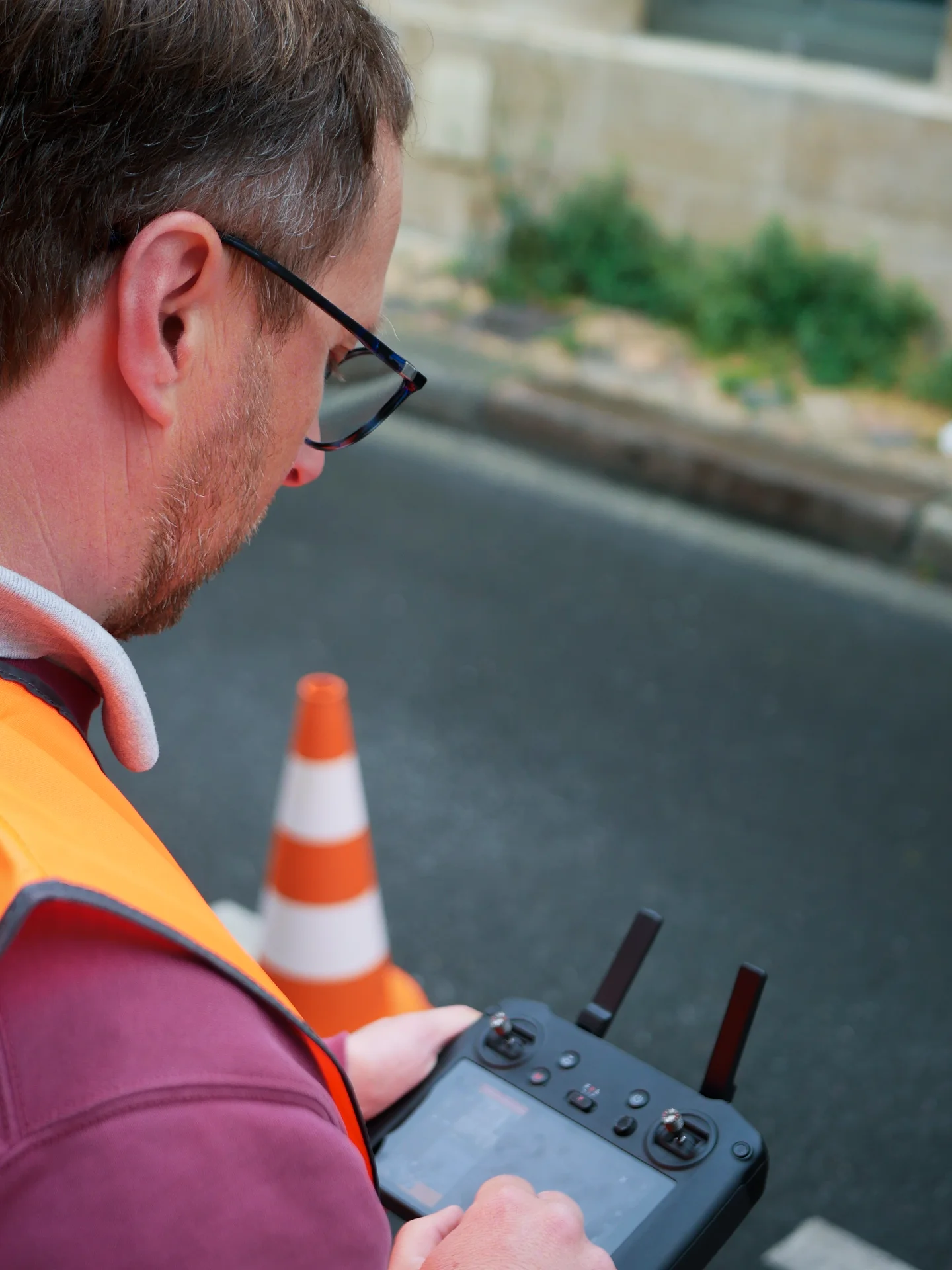 Télépilote préparant un vol d’inspection de toiture avec un confrère assurant le contrôle des flux au sol, cône de signalisation visible