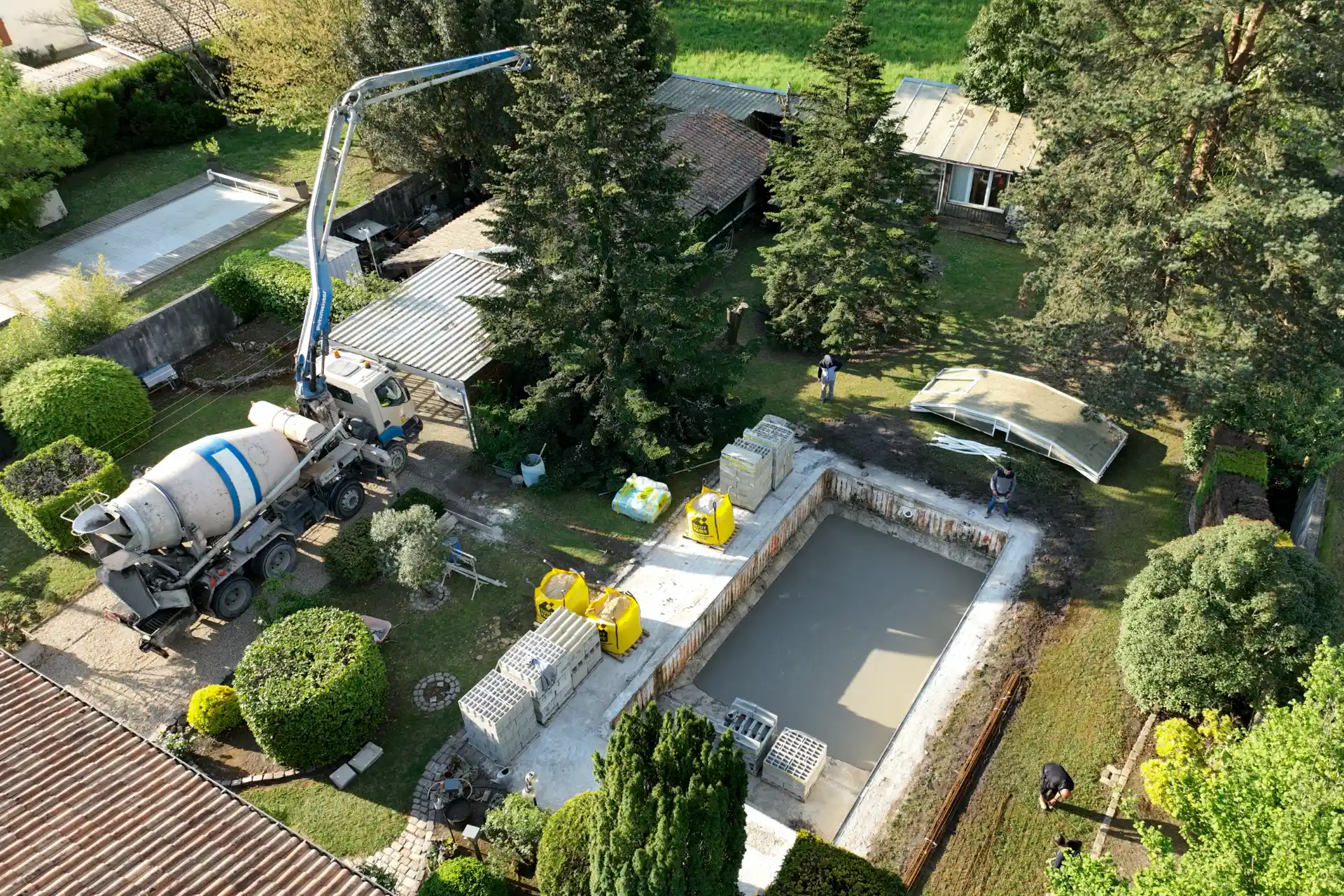 Vue aérienne par drone d’une pompe à béton en train de couler le radier d’une nouvelle piscine