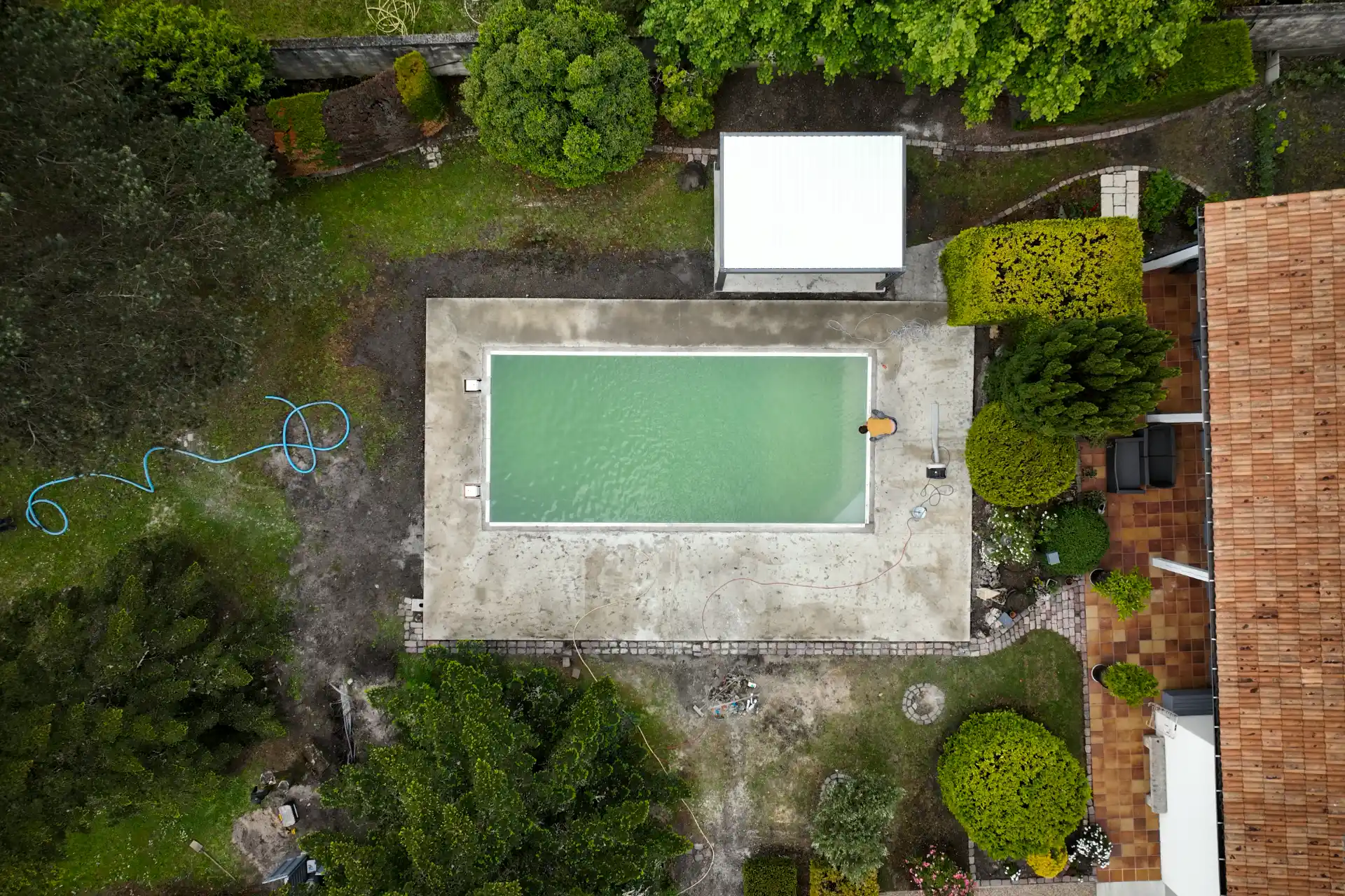 Vue aérienne zénithale par drone du premier remplissage d’une piscine, eau encore trouble et verdâtre